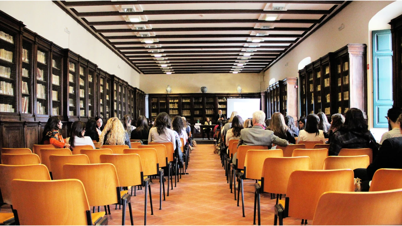 People sat in rows of chairs with a speaker at the front of the room.