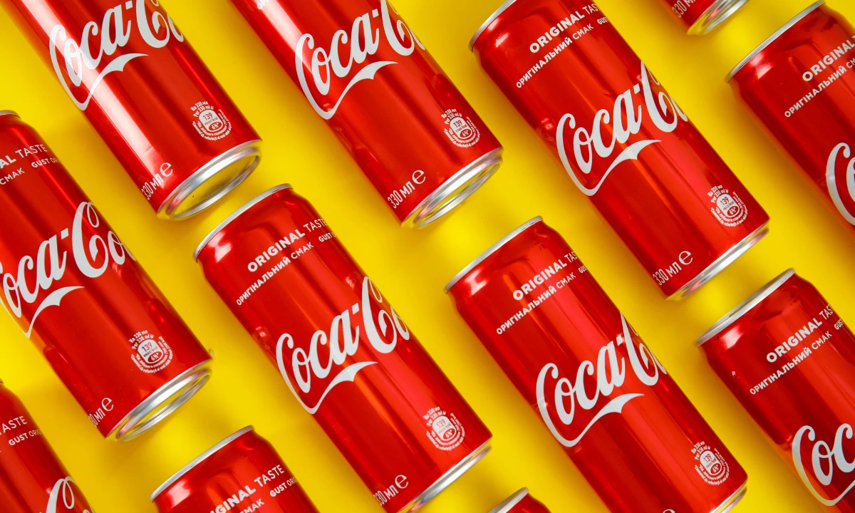 Red Coca Cola cans on a yellow background.