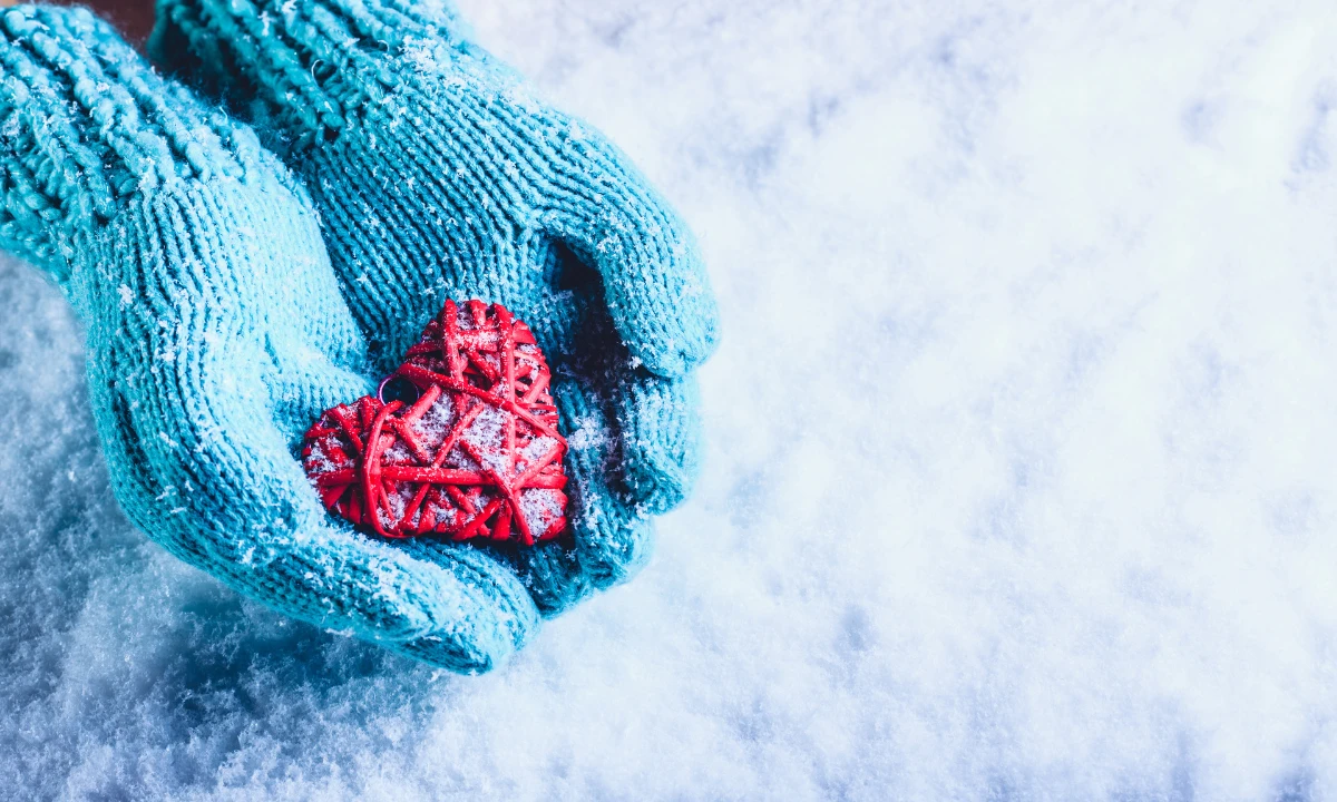 Blue gloved hands hold a red heart.