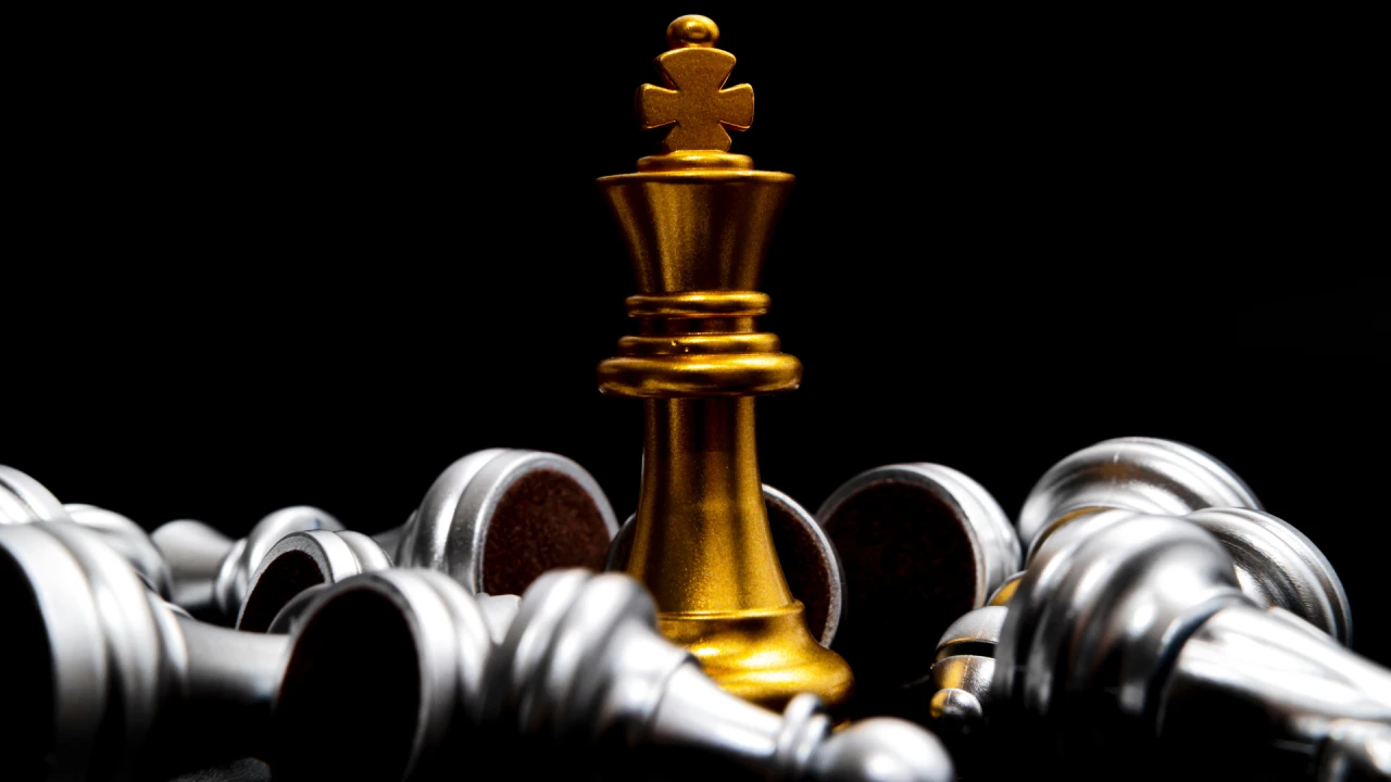 Silver and gold chess pieces set against a black background. The Troubleshooter logo in the foreground.