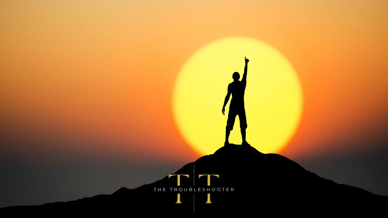 A person standing on a hill silhouetted against the sun.