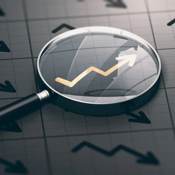 Magnifying glass on a dark chart and focusing on an upwards arrow in gold