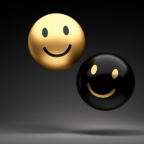 Two gold and black smiley-faced spheres hovering above a grey canvas