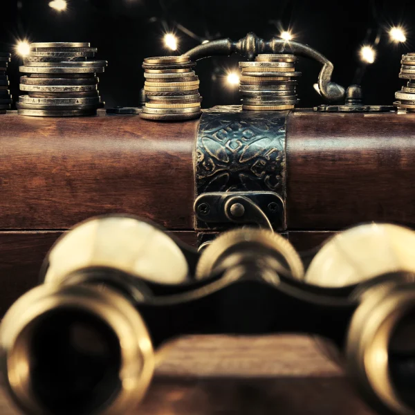 A classic set of gold binoculars sat on mahogany desk with a gun laid behind