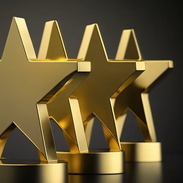 Three gold awards in the shape of a start, glimmering in the light, with a dark backdrop